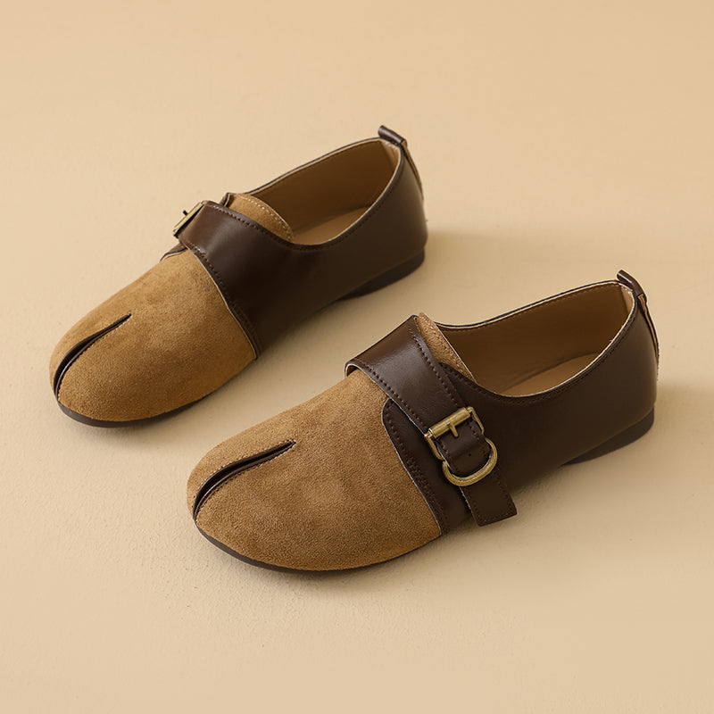 A pair of women's Mary Jane flat shoes in brown and tan suede, featuring a split toe design and a single strap with a gold-tone buckle, set against a solid beige background.
